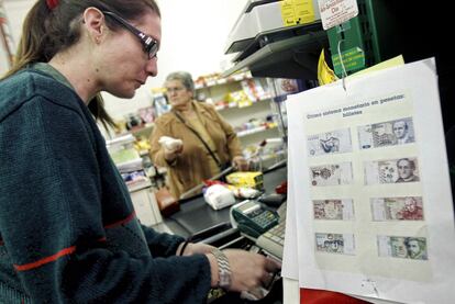 Una cajera de una tienda de comestibles cobra los productos en pesetas en Villamayor de Santiago.