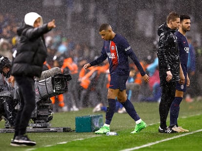 Mbappé sale del campo tras ser sustituido en Marsella, mientras su técnico, Luis Enrique, aparece en primer plano con capucha.