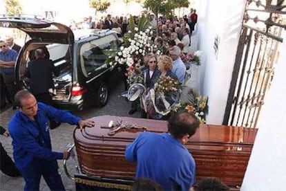 Empleados de la funeraria trasladan el féretro de una de las personas asesinadas en Ayamonte.