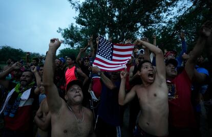 Un grupo de migrantes venezolanos ondean una bandera estadounidense para que los mire un helicóptero de una cadena televisiva que sobrevuela el Río Grande en Matamoros (México), el 12 de mayo, un día después de que se levantaran las restricciones del Título 42. 