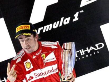 Fernando Alonso sostiene el trofeo en el podio de Abu Dabi.