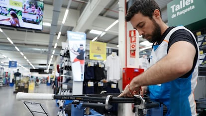 Un operario joven trabaja un taller de raquetas de una tienda de material deportivo en Toledo.