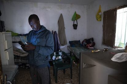 Un inmigrante, consulta su teléfono móvil en el interior del cortijo donde vive en Tierras de Almería, El Ejido.