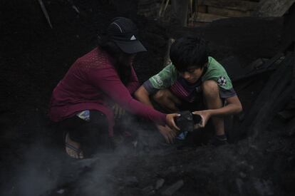 Manuel Mellas lleva trabajando en las carboneras desde los seis años y no gana más de 30 dólares o 25 euros a la semana. En la imagen, Manuel, con su abuela, manipula las ascuas del carbón.