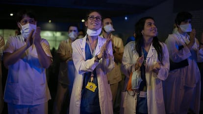 Varios profesionales sanitarios aplauden a las ocho de la tarde a las puertas del Hospital de Sant Pau, en Barcelona, el domingo.