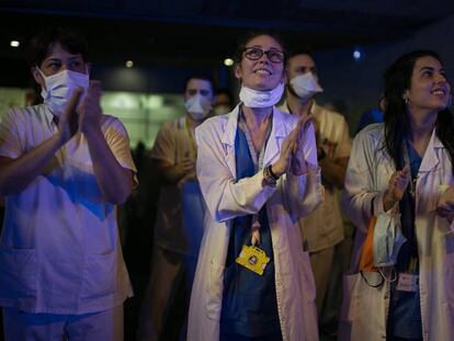 Varios profesionales sanitarios aplauden a las ocho de la tarde a las puertas del Hospital de Sant Pau, en Barcelona, el domingo.