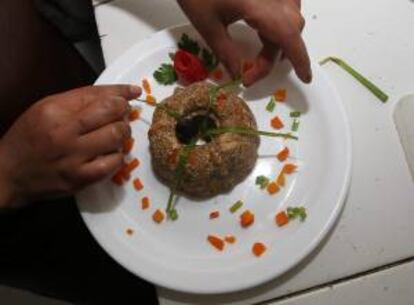 Fotografía de una joven chef de la fundación "Ichuri (palabra aimara que significa "llevar a un niño en brazos") Coffee Restaurant",  al preparar un plato con quinua, en La Paz.