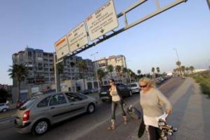 Dos turistas pasan junto a la cola de coches que espera para entrar al pe?n, hoy en la Lnea de la Concepcin (Cdiz). EFE/Archivo