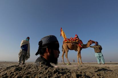 Un joven de 20 años es enterrado con los ojos vendados en arena hasta el cuello durante un eclipse solar, en una playa, cerca de Karachi (Pakistán). Existe la creencia popular de que este ritual puede tener beneficios para la salud. 