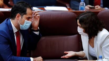 Madrid premier Isabel Díaz Ayuso (r) talks with her deputy Ignacio Aguado in the regional parliament.