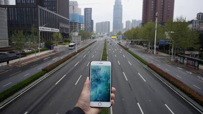 Una persona sostene un teléfono móvil frente a una carretera casi vacía en Wuhan, China, el pasado 31 de marzo.