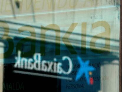 Logotipo de Caixabank reflejado en una ventana de una oficina de Bankia