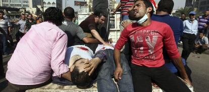 Los manifestantes retiran a los heridos de la plaza Rams&eacute;s, de El Cairo.