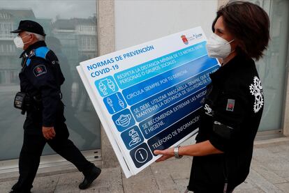 Una mujer coloca un cartel informativo en una calle de Viveiro (Lugo), este martes.
