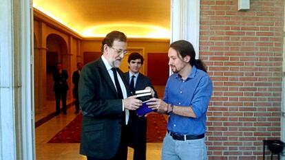 Pablo Iglesias presents Rajoy with a gift on his arrival at La Moncloa.