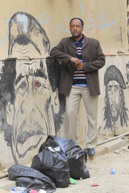 Un transeúnte posa al lado de una caricatura de Gadafi en una calle de Tripoli.