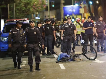 Policiais ao lado do corpo de um homem morto, perto do estádio do Maracanã no dia da cerimônia de abertura.