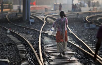 Una mujer india anda en una estación de trenes tras defecar en medio de los raíles, una práctica común.