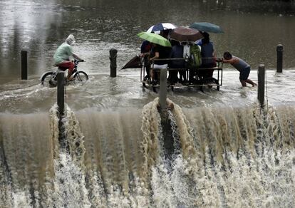 Un grupo de filipinos, montados en un carro improvisado, cruza una presa desbordante durante una lluvia torrencial en la ciudad de Las Pinas, al sur de Manila, (Filipinas).