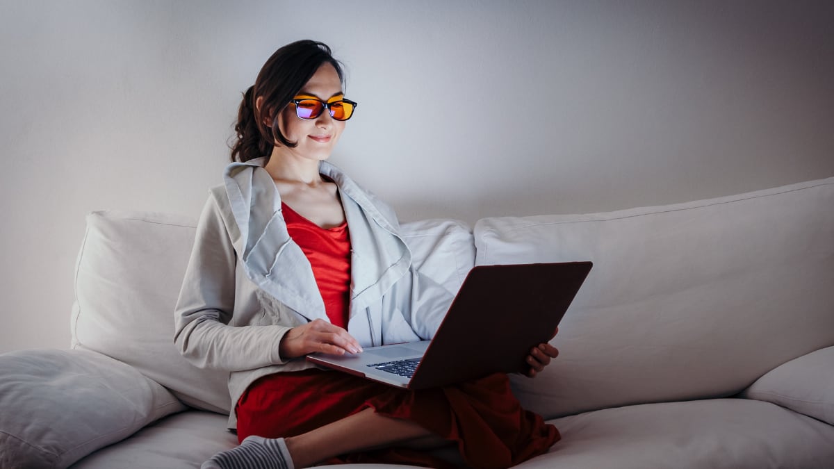 Mujer joven con gafas de bloqueo de luz azul trabajando con el portátil.