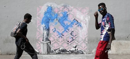 Dos jóvenes pasan frente a una supuesta obra de Banksy, en París.
