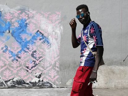Dos jóvenes pasan frente a una supuesta obra de Banksy, en París.