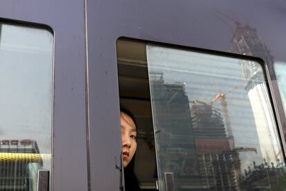 Una mujer mira por la ventana de un autobús que circula por el Distrito Central de Negocios de Pekín (China).