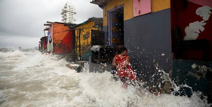 Una mujer es salpicada por el oleaje durante la marea alta, en Bombay.