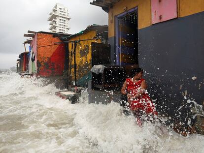 Una mujer es salpicada por el oleaje durante la marea alta, en Bombay.