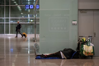 Una persona sin techo durmiendo en la Terminal 1 del aeropuerto de Barcelona