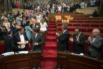 Catalan deputies applaud the passing of the referendum law in a half-empty regional parliament.