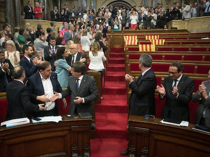 Catalan deputies applaud the passing of the referendum law in a half-empty regional parliament.