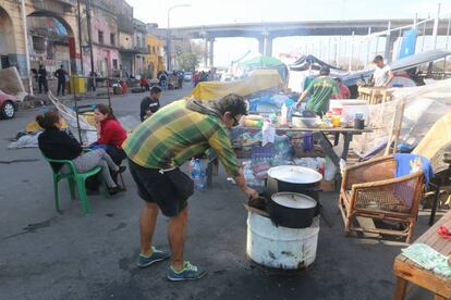 Un hombre cocina en el acampe frente al conventillo incendiado.