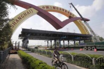 Una mujer en bicicleta pasa junto a un arco que se&ntilde;ala la &quot;Zona de libre comercio de Shangh&aacute;i&quot;, en Shangh&aacute;i (China).