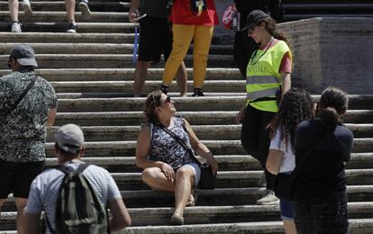 Una policía pide a una mujer sentada en la escalinata de la Plaza de España en Roma que se levante.