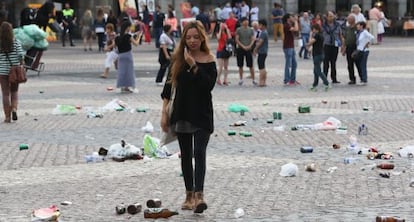 A passer-by navigates the beer bottles and other trash left behind by soccer fans in Madrid's Plaza Mayor.