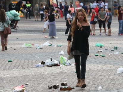 A passer-by navigates the beer bottles and other trash left behind by soccer fans in Madrid's Plaza Mayor.