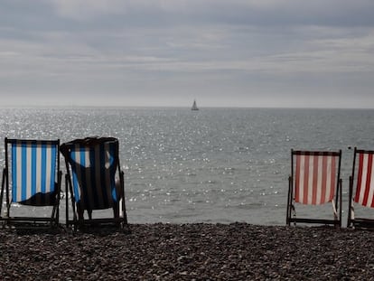 Una mujer toma el sol en una tumbona junto al mar en un día soleado en la playa de Brighton (Reino Unido).