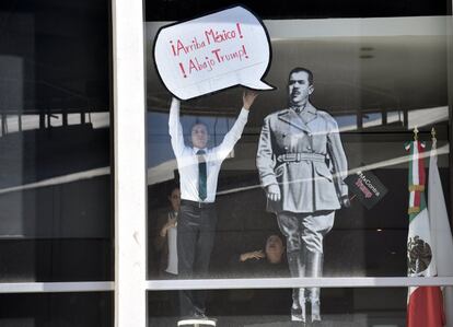 Un hombre sostiene un cartel contra el candidato republicano a la presidencia de los Estados Unidos Donald Trump, en la ventana de un edificio público en Ciudad de México.