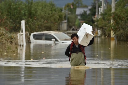 Un hombre atraviesa el agua estancada tras la inundación con objetos rescatados de su casa después del tifón Hagibis, en Nagano el 14 de octubre de 2019.