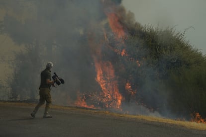 Una persona con cámara de vídeo graba un fuego en el polígono industrial de A Rúa, Ourense, este sábado.