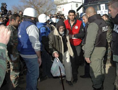 Un miembro de la Media Luna Roja Siria ayuda a un hombre en la zona sitiada de Homs.