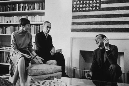 Leo Castelli (segundo por la derecha) y su esposa Antoinette conversan con Jasper Johns en el apartamento de la pareja. La pintura del fondo es una de las célebres banderas de Johns.