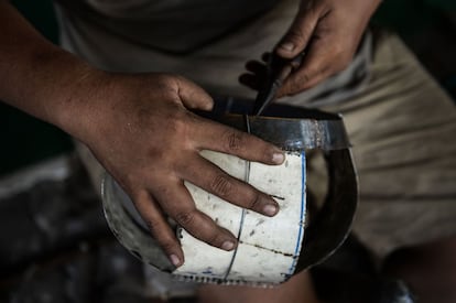 Las manos de un hombre trabajando los paneles de acero para la fabricación de cuencos de limosna tradicionales budistas que se utilizarán durante el 'Khao Phansa'. Esta festividad no se celebra en un día en concreto, sino que varía debido a las diferencias entre el calendario lunar y solar y coincide con la luna llena del octavo mes del calendario lunar tailandés.