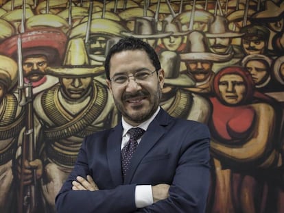 Mart&iacute; Batres frente a una reproducci&oacute;n de un mural de Siqueiros. 