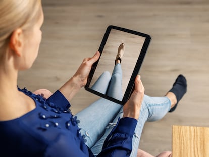 A woman tries on some shoes virtually using an electronic tablet.