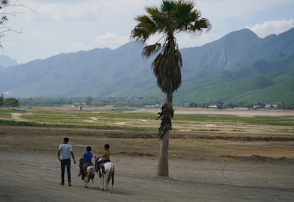 Niños montan a caballo frente a la presa de La Boca, prácticamente vacía, que lleva agua a la ciudad de Monterrey (Estado de Nuevo León), en julio de 2022.