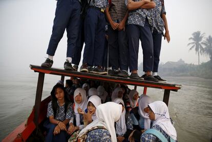 Estudiantes navegan sobre el techo de una barca que cruza el río Musi hacia su escuela en Palembang, en la isla de Sumatra (Indonesia).