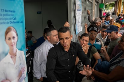 Un trabajador del dispensario Disfarma intenta calmar a los pacientes que esperan sus medicamentos.