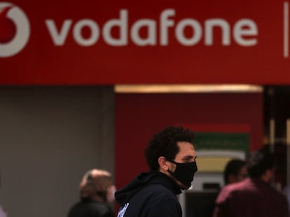 Un hombre camina ante un cartel de Vodafone.